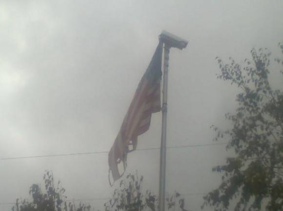Tattered American flag, with a security camera on it. Symbol of the times?